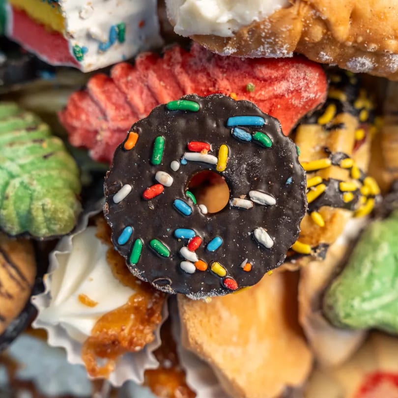 Close-up of a chocolate sprinkle cookie among other colorful Italian deli pastries.